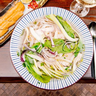 Phở gà mit Huhn und Kräutern in einer blau gestreiften Schale